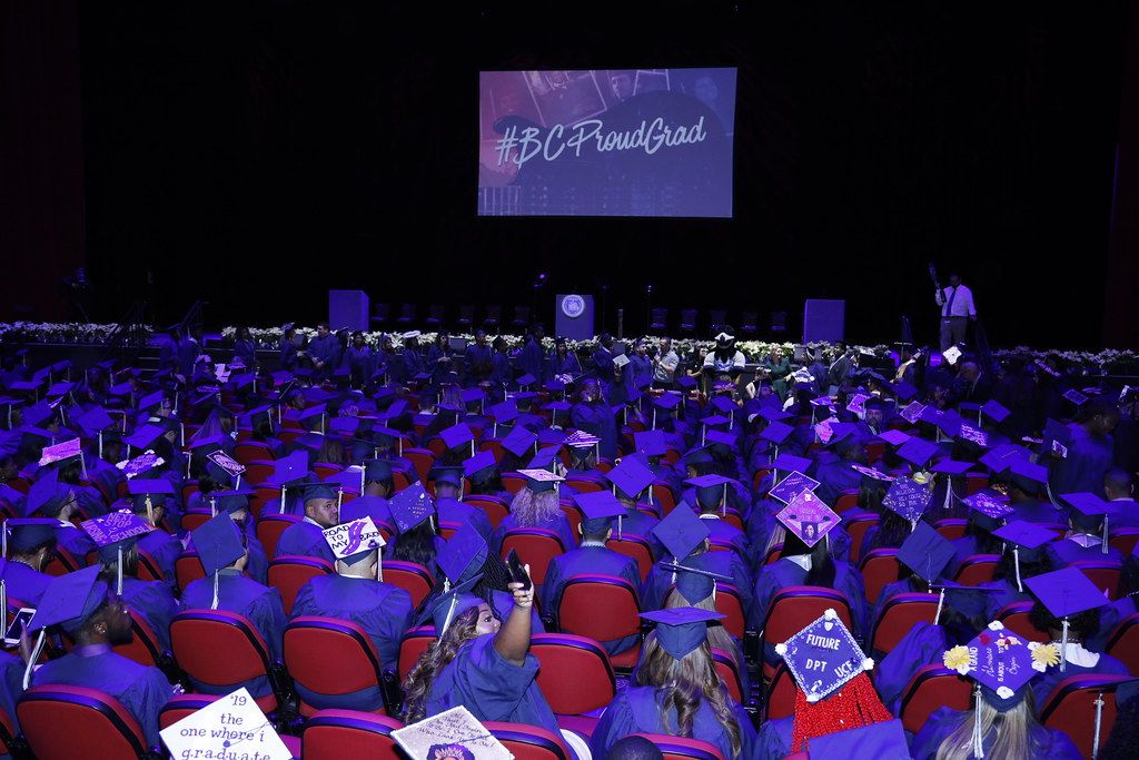 BC graduates sitting before a screen that reads #BCProudGrad