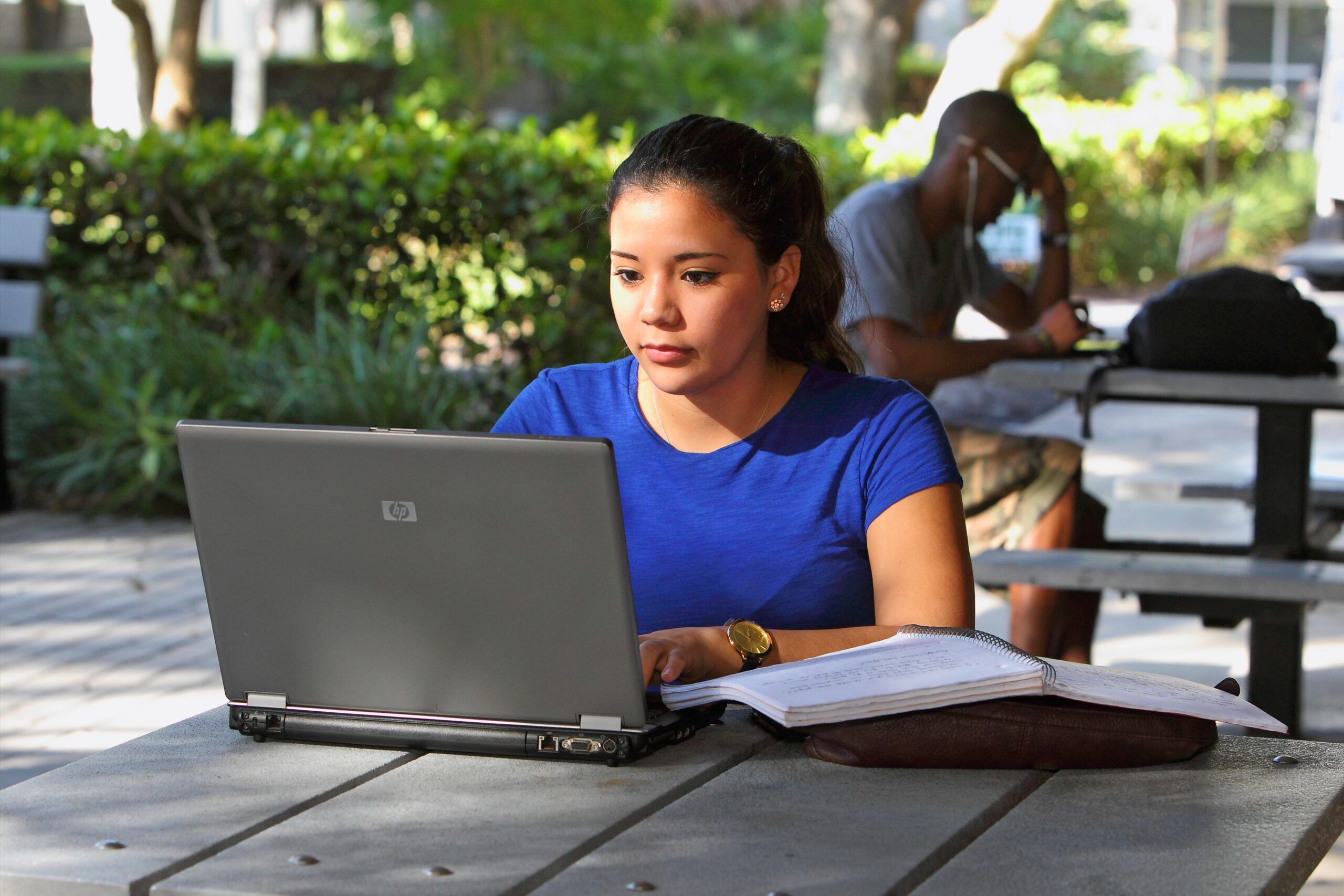 Young woman sitting outdoors looking at her laptop