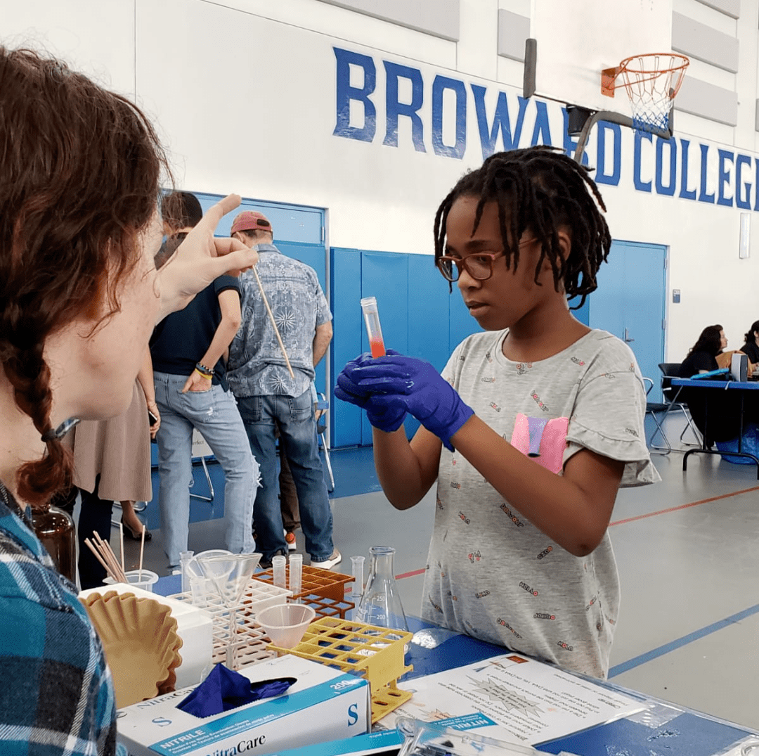 Young students looking at beaker at a STEM event booth
